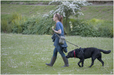 Side view of woman walking with dog at park