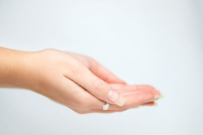 Cropped hand of woman gesturing against white background