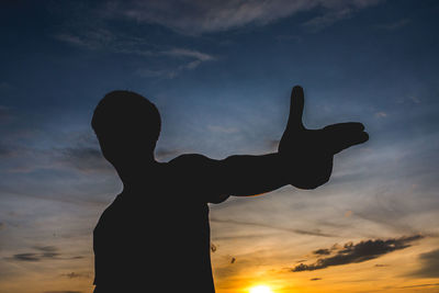 Silhouette man gesturing against sky during sunset