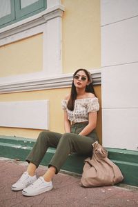 Portrait of a smiling young woman sitting against wall