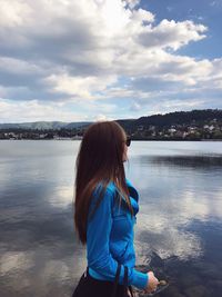 Woman looking at lake against sky