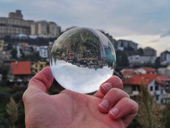 Close-up of hand holding crystal ball against cityscape