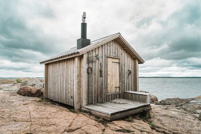 Wooden hut on beach against sky