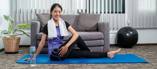 Young woman using mobile phone while sitting in gym