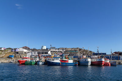 Boats moored in sea against clear blue sky