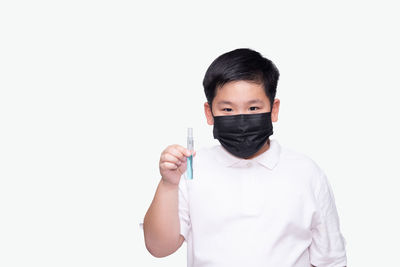 Portrait of boy standing against white background