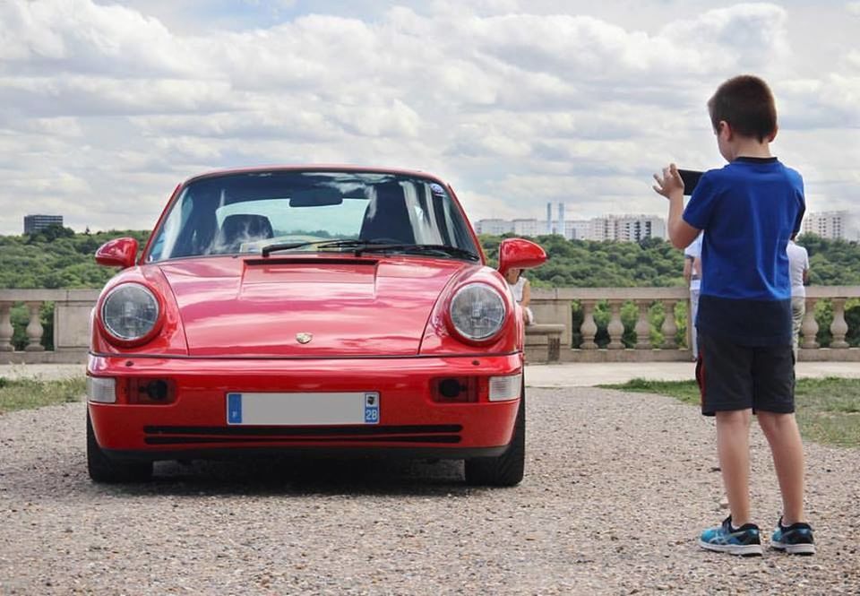 REAR VIEW OF BOY STANDING ON CAR AGAINST SKY