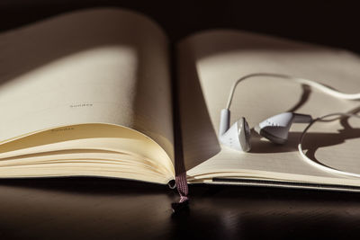 Close-up of headphones with book on table