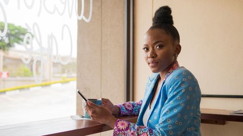 Side view of young woman using digital tablet while standing at home