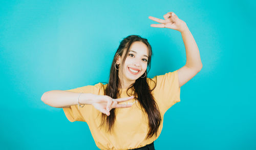 Portrait of young woman gesturing against blue background