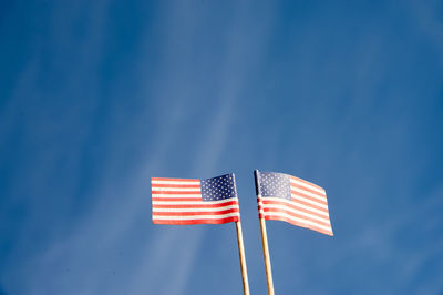Low angle view of small american flags against blue sky