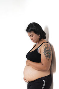 Woman looking away while standing against white background