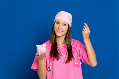 Portrait of smiling young woman standing against blue background