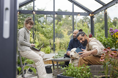 Smiling friends sitting in greenhouse