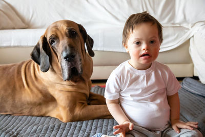 Disabled boy with dog sitting on carpet at home