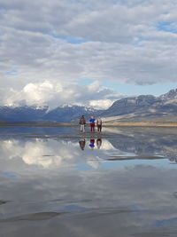 People on lake against sky