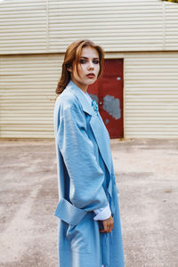 Fashionable young woman wearing blue overcoat in city