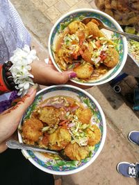 High angle view of woman holding food in bowl on table