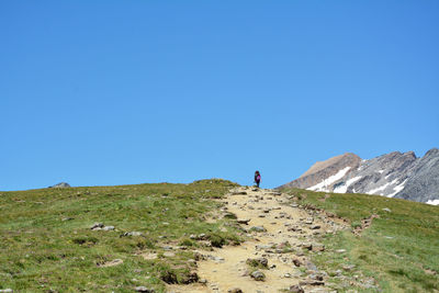Mid distance of woman walking on land against clear blue sky