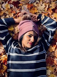 High angle portrait of young woman lying on autumn leaves