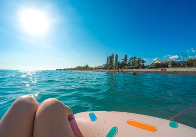 Low section of woman relaxing by sea against sky