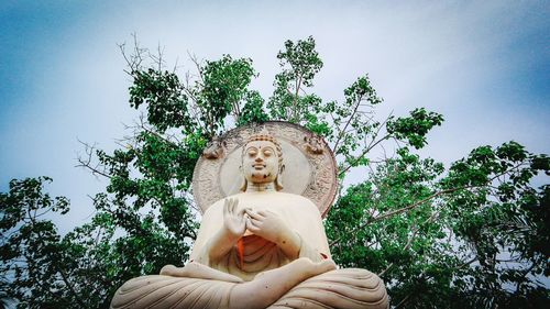 Low angle view of statue against trees against sky