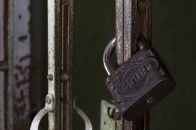 Close-up of rusty padlock hanging on gate