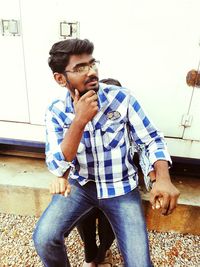 Young man sitting against wall