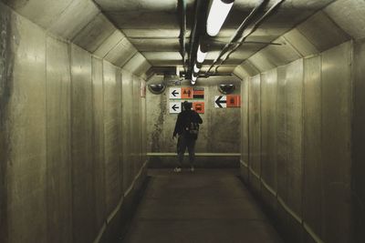 Rear view of man standing in illuminated tunnel