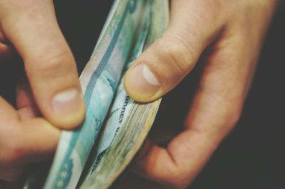 Close-up of hand holding paper currency indoors