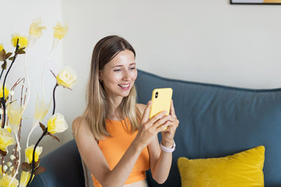 Young woman using mobile phone while sitting at home