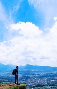 Man photographing woman standing on mountain against sky