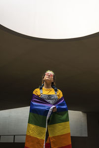 Young woman standing with rainbow flag