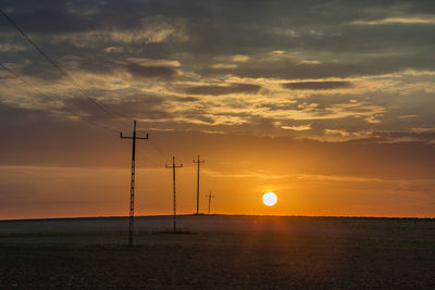 Sunset behind the horizon and electric poles in the field