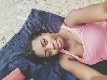 Portrait of woman lying on blanket at beach