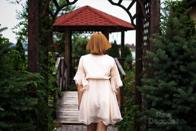 Rear view of woman with umbrella walking in garden