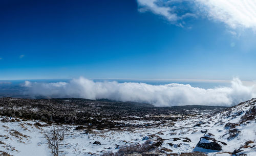 Scenic view of snowcapped mountains against blue sky