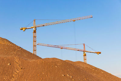 Low angle view of crane against clear blue sky