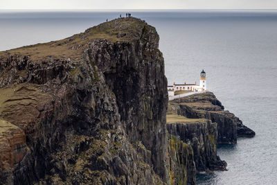 Lighthouse by sea against sky