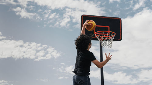 Low angle view of man playing basketball against sky