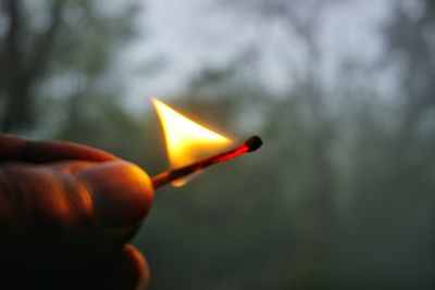 Cropped image of hand holding lit candle