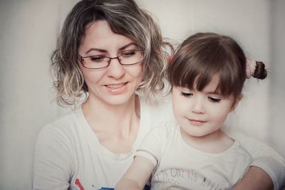 Close-up of cute daughter with smiling mother at home