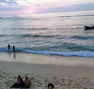 People on beach against sky during sunset