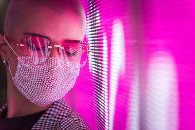 Close-up of young woman with shaved head standing against abstract backgrounds