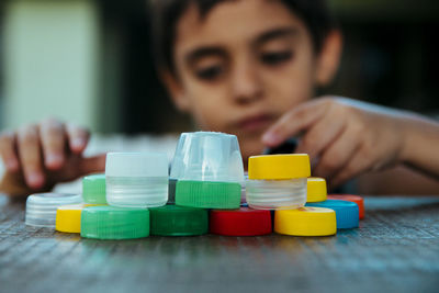 Boy playing with bottle caps on table