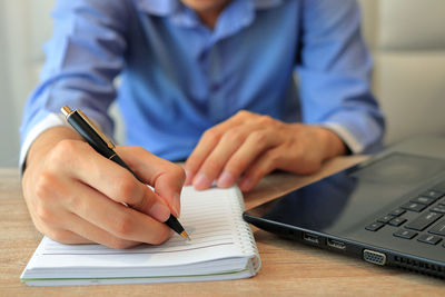 Midsection of man using mobile phone on table