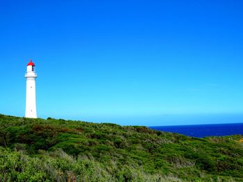 Lighthouse by sea against sky