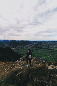 Rear view of woman standing on mountain against sky