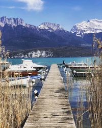 Pier over lake by snowcapped mountains against sky
