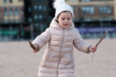 Little girl is playing on an empty beach on a cold day